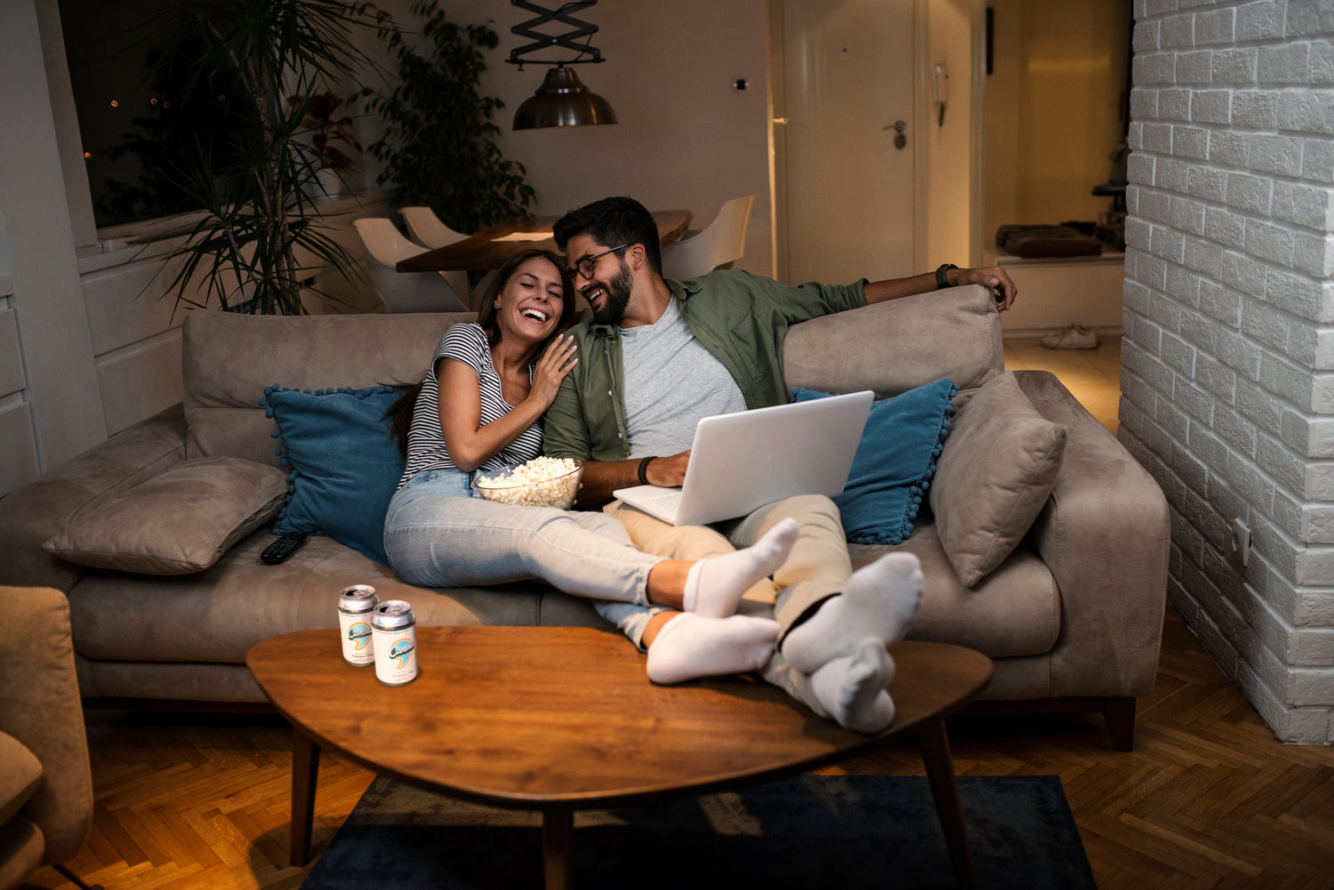 A couple sitting on the couch watching a movie on a laptop and enjoying Comma