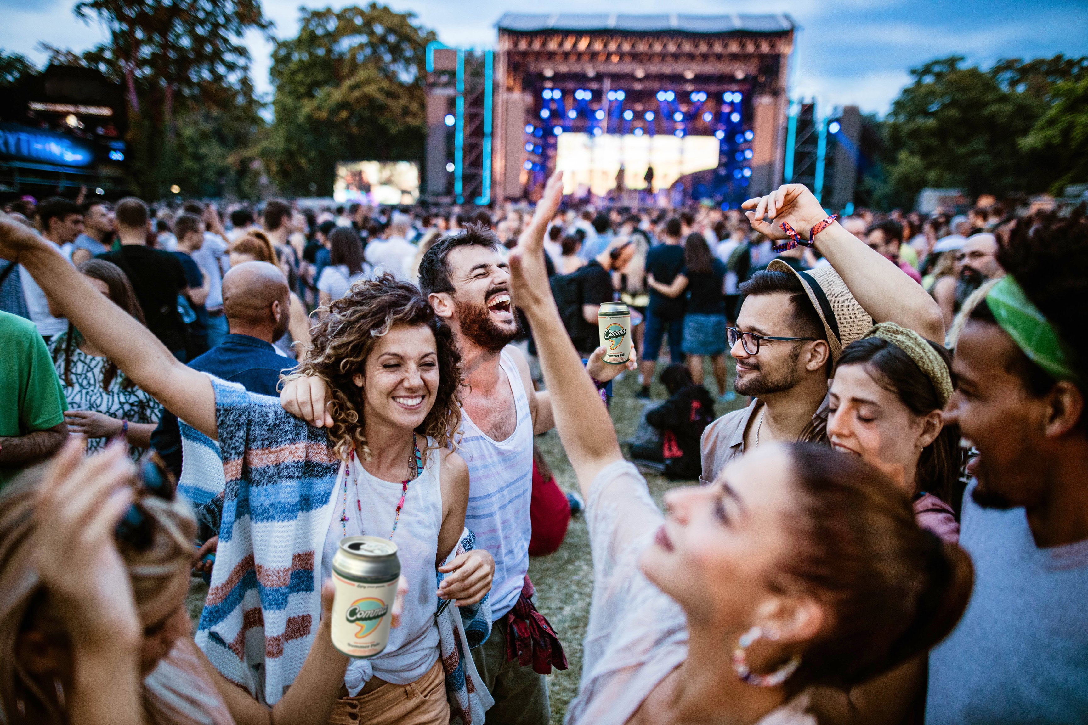 A group of concert goers dancing and drinking Comma